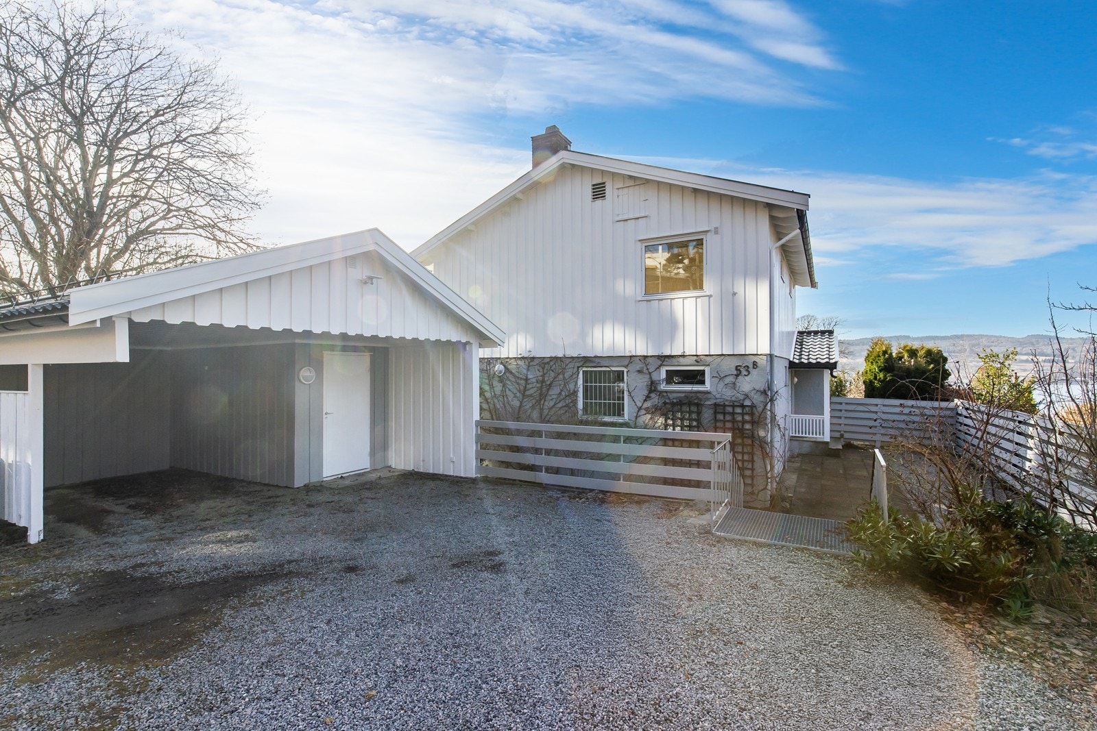 Stor carport med isolert bod og gruslagt gårdsplass. Galleribilde