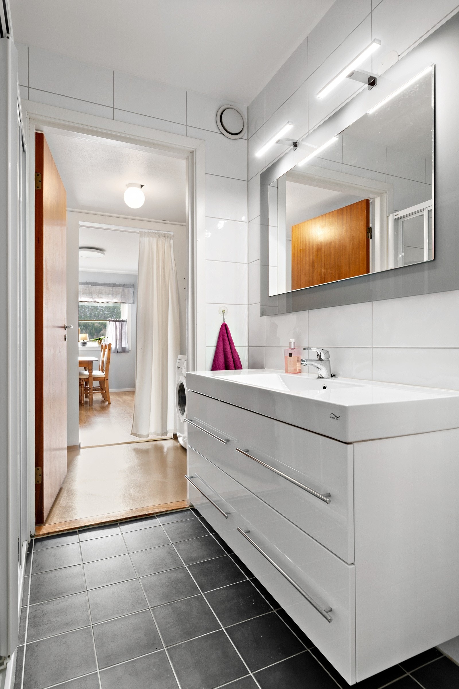 Rommet er innredet med dusjnisje med skyvedør av glass og baderomsinnredning. Speil og belysning over innredningen. Galleribilde