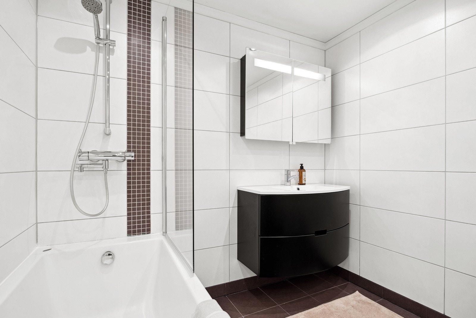 Innredningen består av nedfelt servant med skuffeseksjoner, speilskap, badekar og vegghengt toalett. Galleribilde