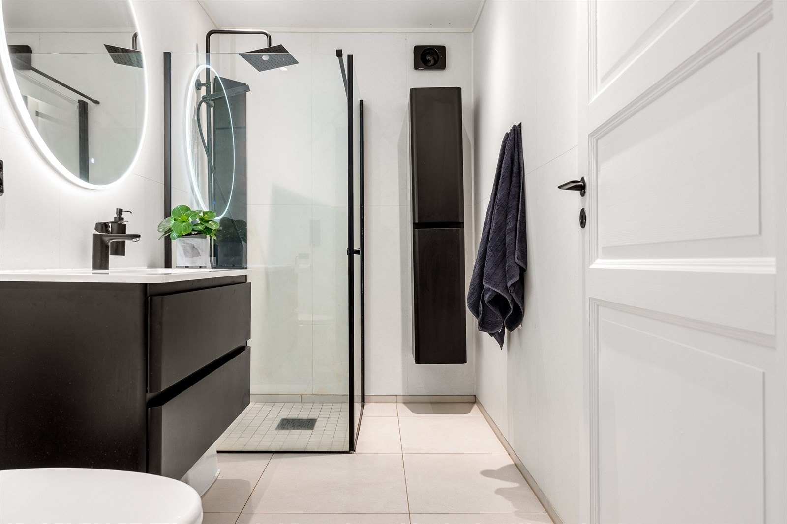 Badet inneholder toalett, helstøpt servant med skuffer under i slette fronter, speil med integrert lys og dusjdører i klart glass. Galleribilde