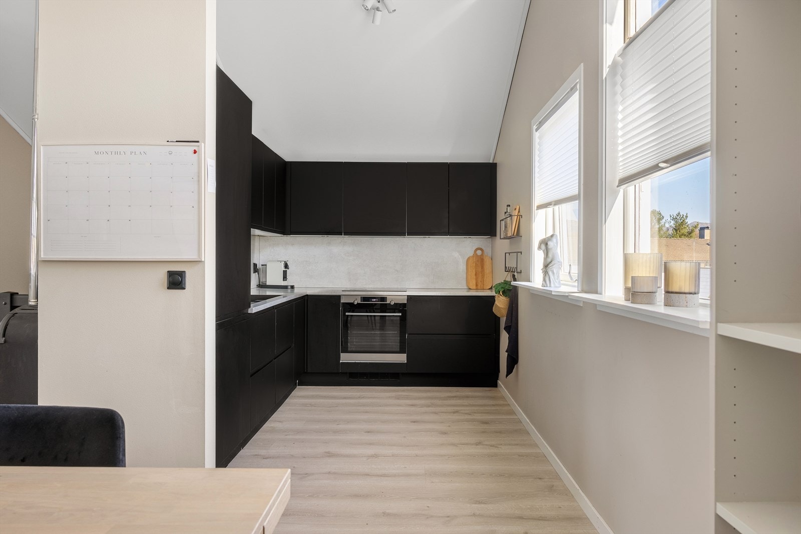 Like ved stuen finner vi kjøkkenet. Kjøkkenet har innredning med slette fronter, laminat benkeplate, over benkeplaten er det benyttet laminatplate, oppvaskkum og ventilator. Galleribilde