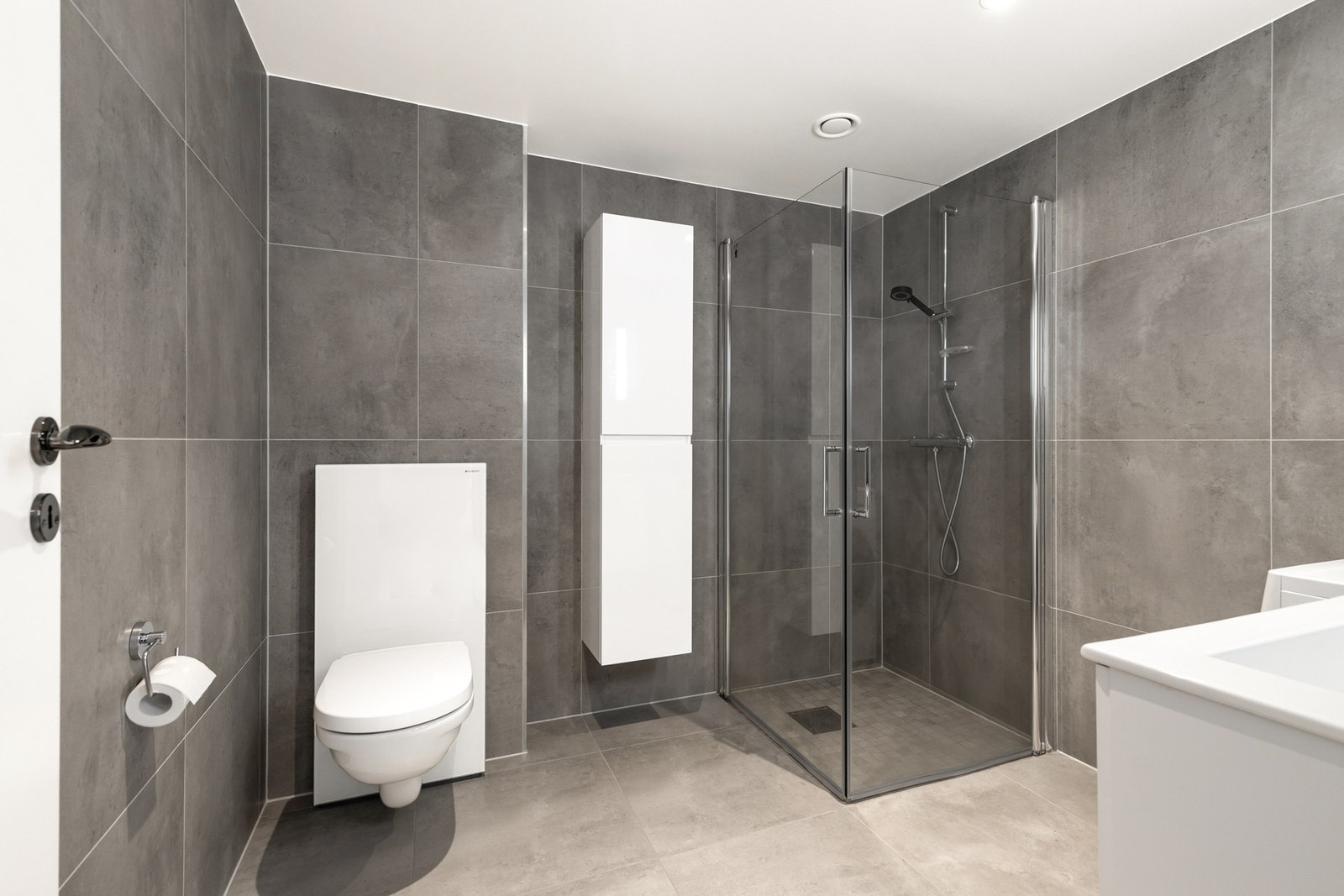 Rommet er videre utstyrt med vegghengt toalett, dusjhjørne med innfellbare dører og servantinnredning med heldekkende servant Galleribilde