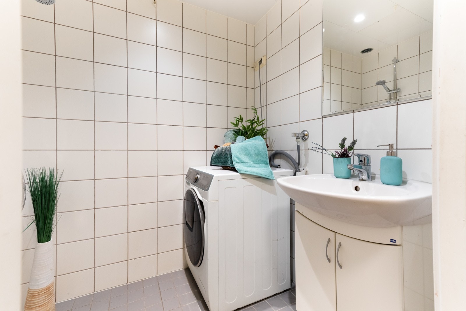 . Her finner du en romslig dusjsone i hjørnet, opplegg for vaskemaskin, servant med speil over samt downlights i taket Galleribilde