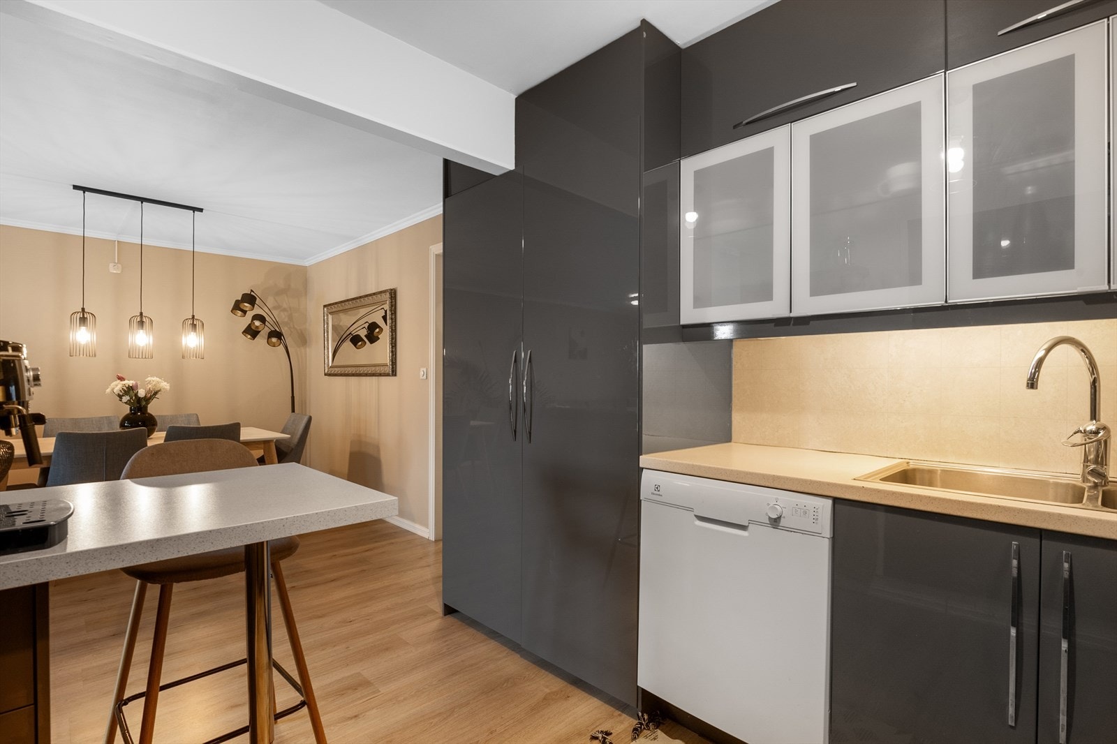 Kjøkkenet har en praktisk vinkelform med over- og underskap i delvis blanke, heldekkende fronter og delvis fronter i et frostet utseende samt benkeplate i laminat. Galleribilde