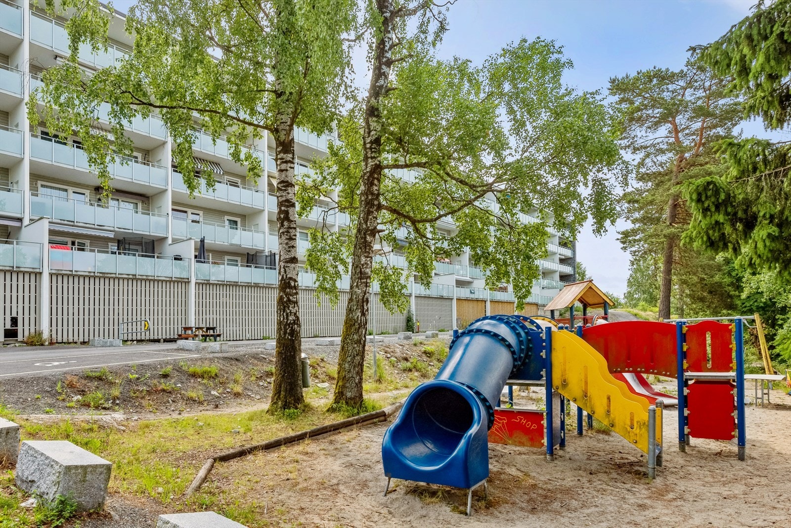 På begge sider av boligblokken er det lekeplass og sittebenker til glede for liten og stor. Galleribilde