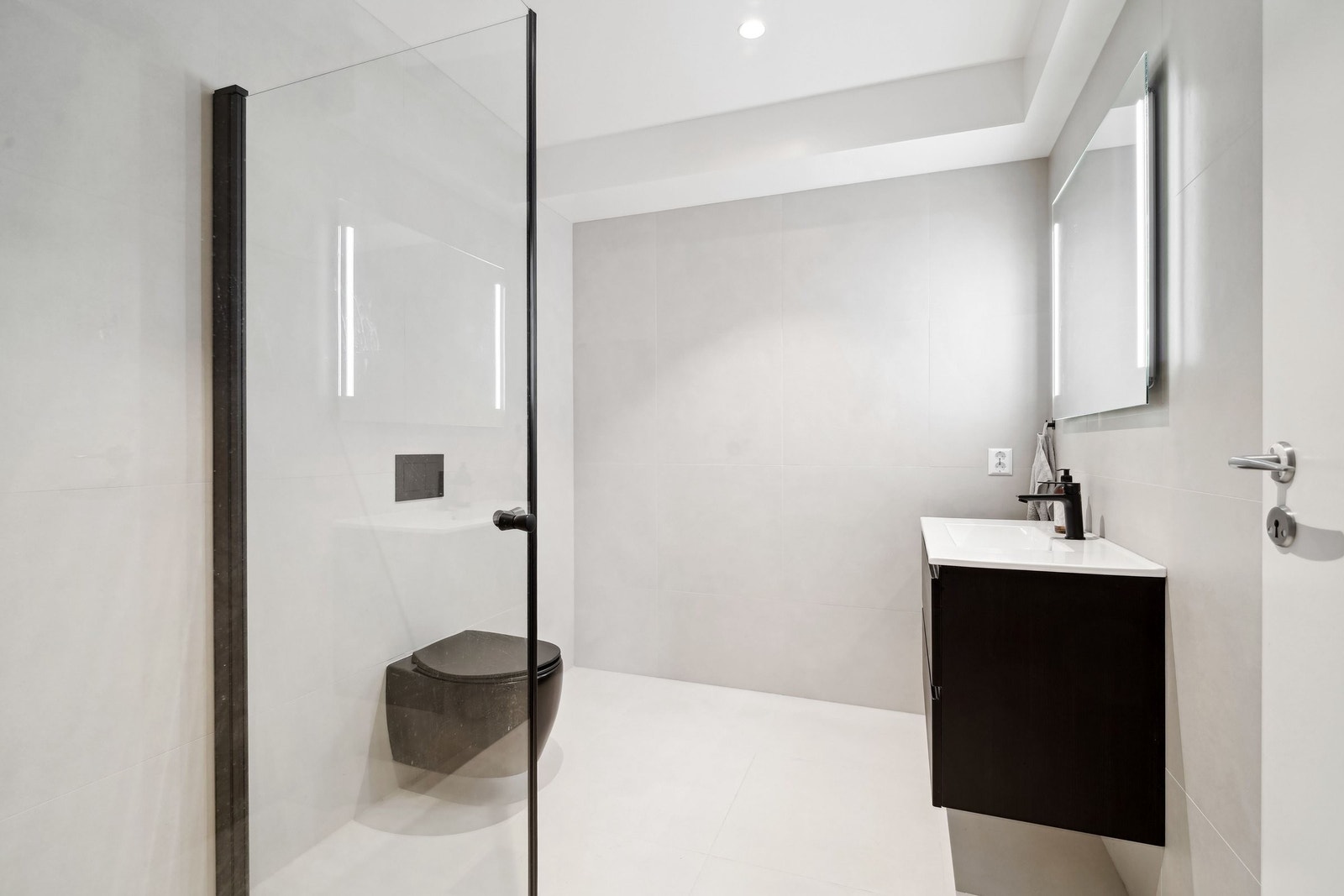 Badene har 60x60 flis i en behagelig dus fargetone. Begge bad har brede regnfall-dusjhoder i sort utførelse. Galleribilde