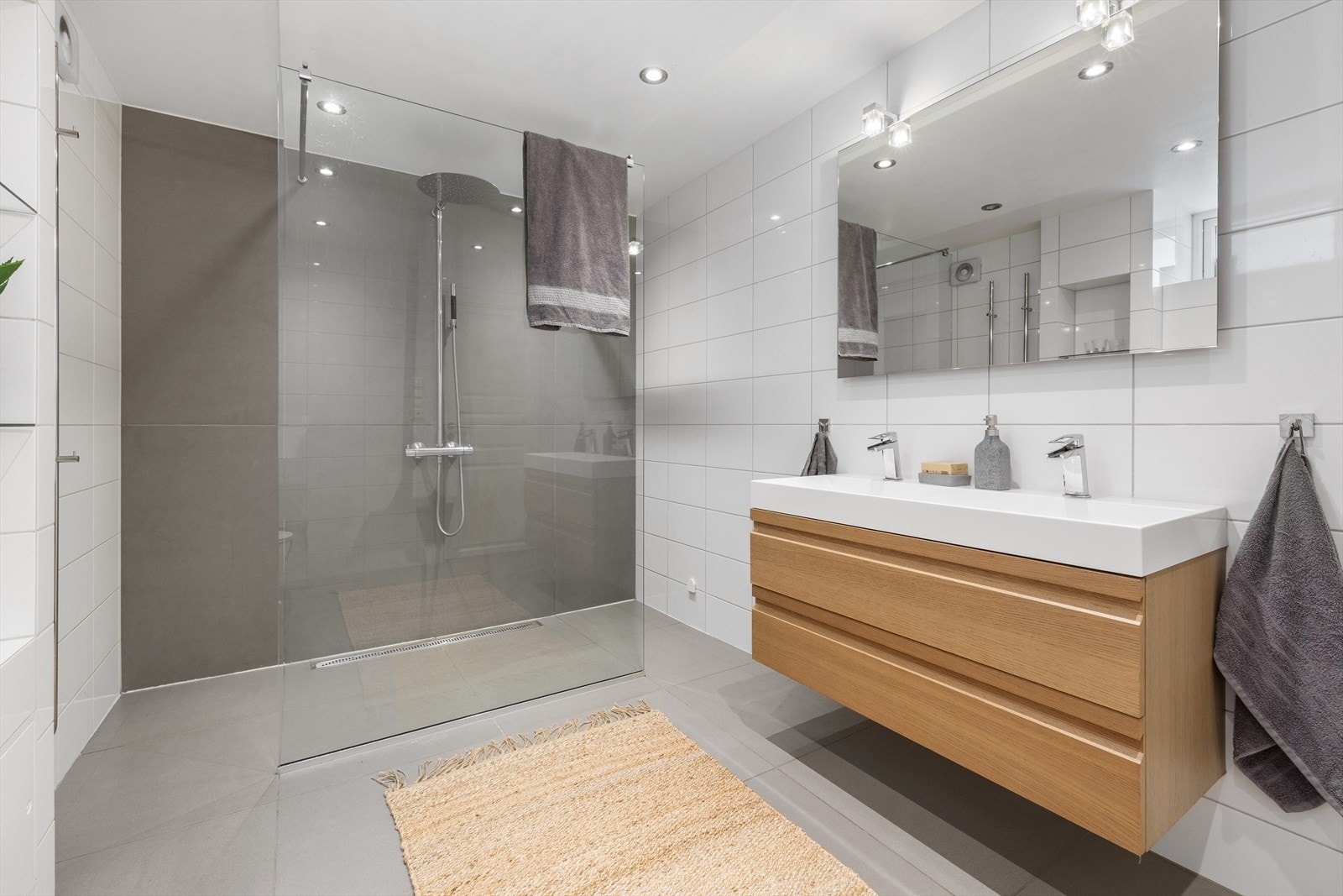 Underetasjens andre bad er boligens største, med nøytrale flisoverflater og en stor dusjnisje med midtstilt glassvegg i front, samt regnfallsdusj. Galleribilde