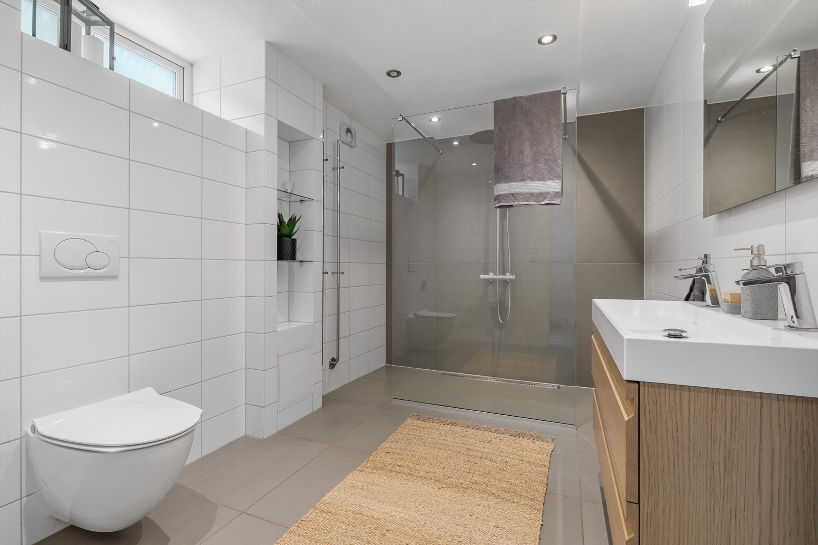 Videre består innredningen av vegghengt toalett og en hendig innfelt hylle, samt bred skuffeseksjon med nedfelt servant og to kraner. Galleribilde