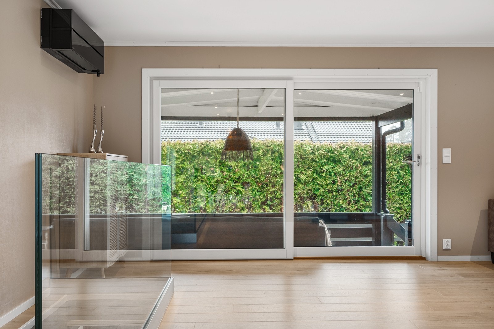 Fra stuen er det en skyvedør fra 2020 med to store glassfelt som fører ut til overbygd veranda. Galleribilde