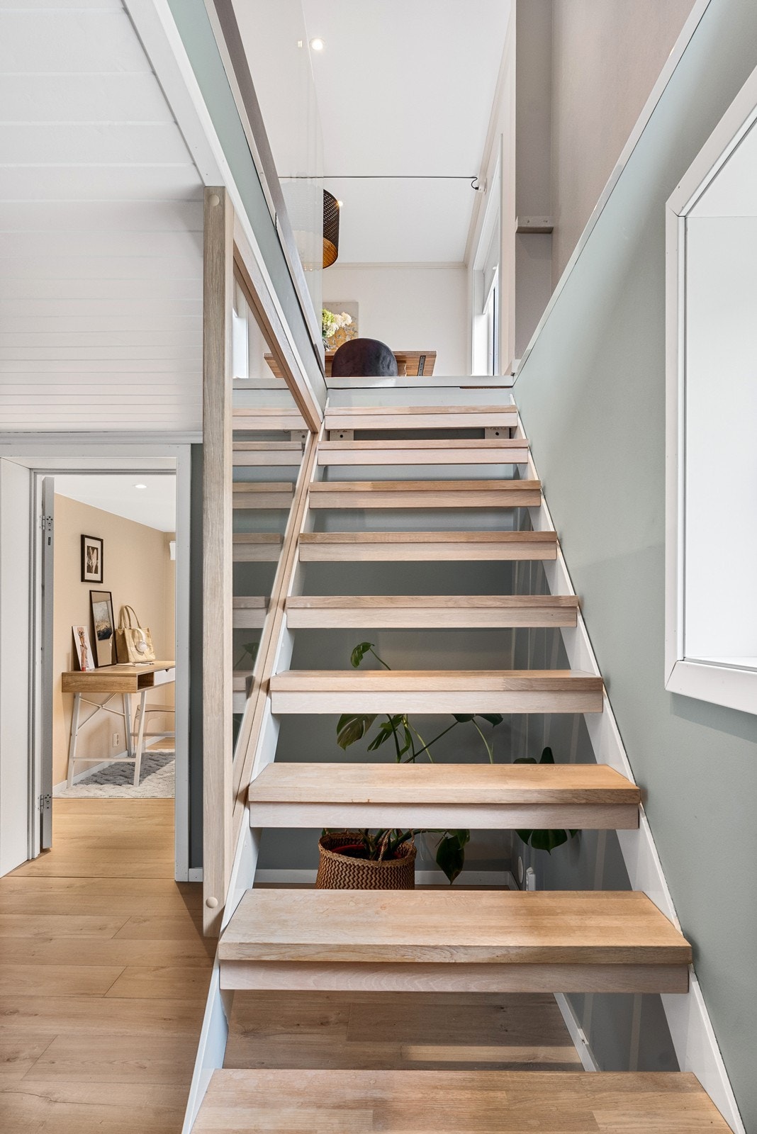 Eiketrappen som fører ned til boligens underetasje har glassplater som rekkverk. Galleribilde