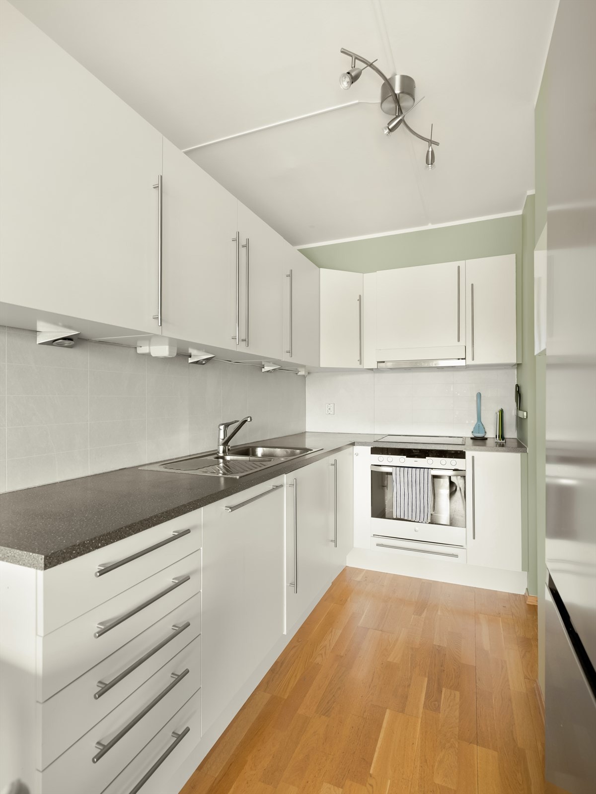 Kjøkkenet har slette fronter på over og underskap, samt laminert benkeplate med nedfelt vask og platetopp Galleribilde