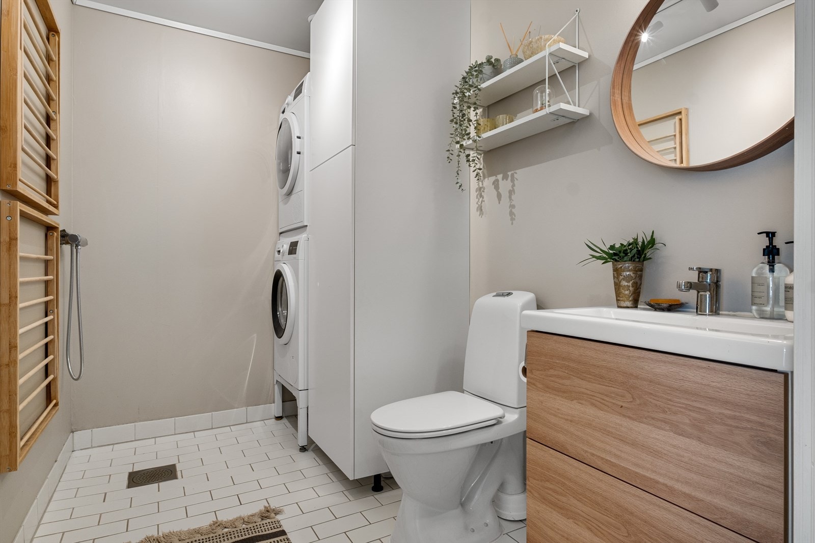 Lyst og separat vaskerom med malte/ tapetserte overflater og flislagt gulv med varmekabler. Rommet er innredet med wc, dusj, servant i innredning, skapinnredning og opplegg for praktisk vaskesøyle. Galleribilde