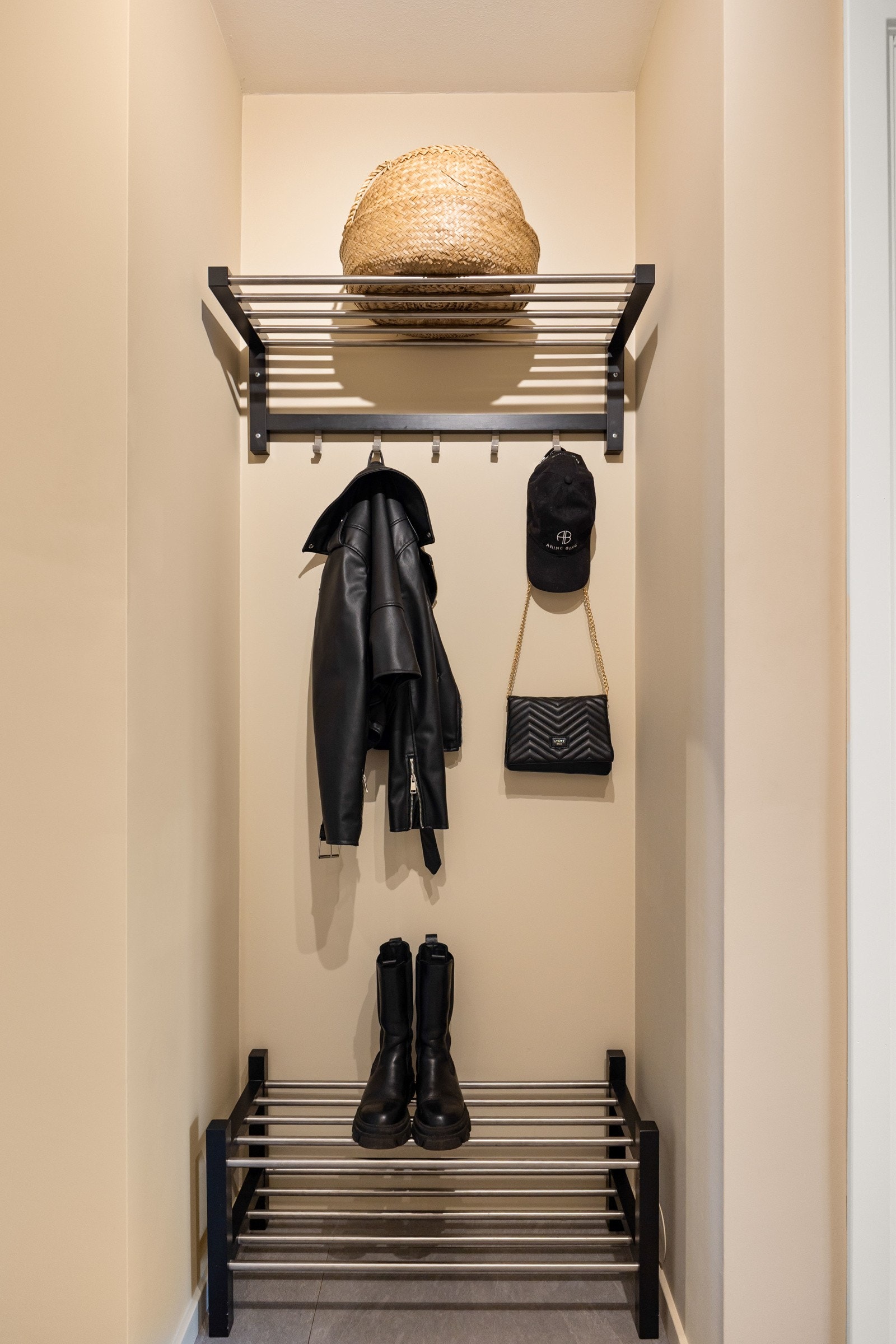 Sort metallhylle med kleskroker og skohylle. Galleribilde