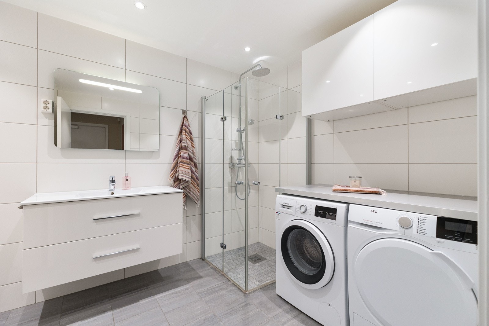 Moderne baderom med fliser på vegger og gulv. Dusj med glassdører. Galleribilde