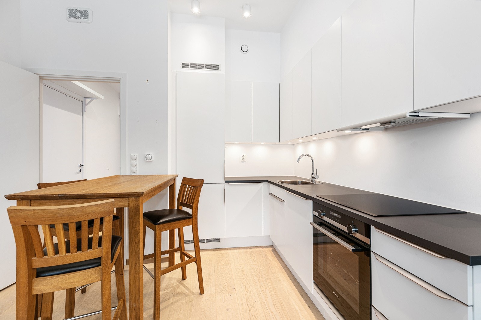 Kjøkkenet har en vinklet innredning med god lagringskapasitet i overskap, underskap og skuffeseksjon Galleribilde