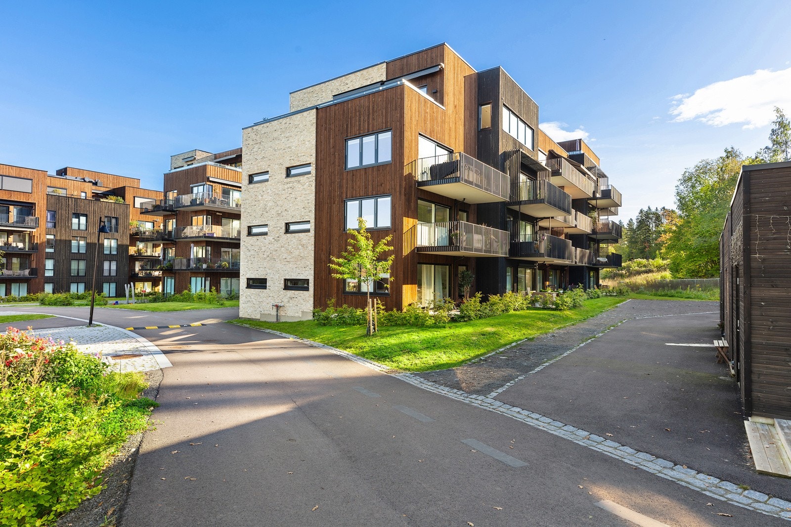 Her er forseggjorte fellesarealer pent opparbeidet med plener, hekker og diverse beplantning Galleribilde