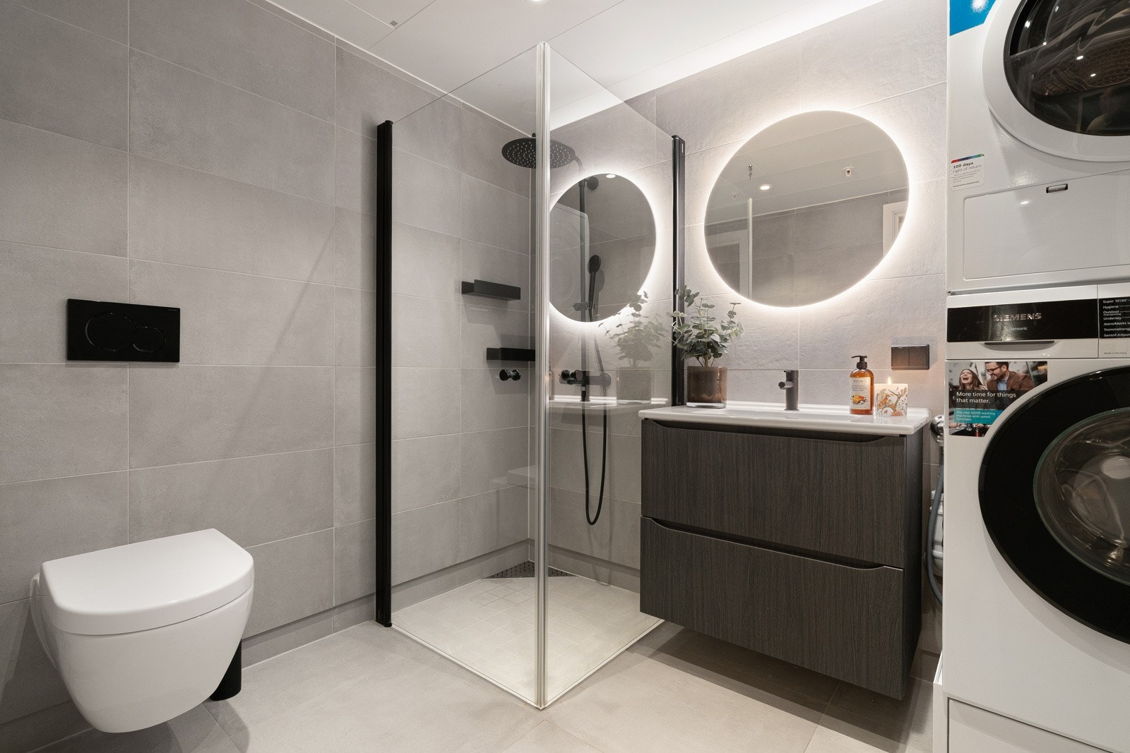 Badet framstår lekkert med store fliser og stilig innredning med sorte detaljer. Stort dusjhjørne med innfellbare glassdører. God plass til vaskemaskin. Galleribilde