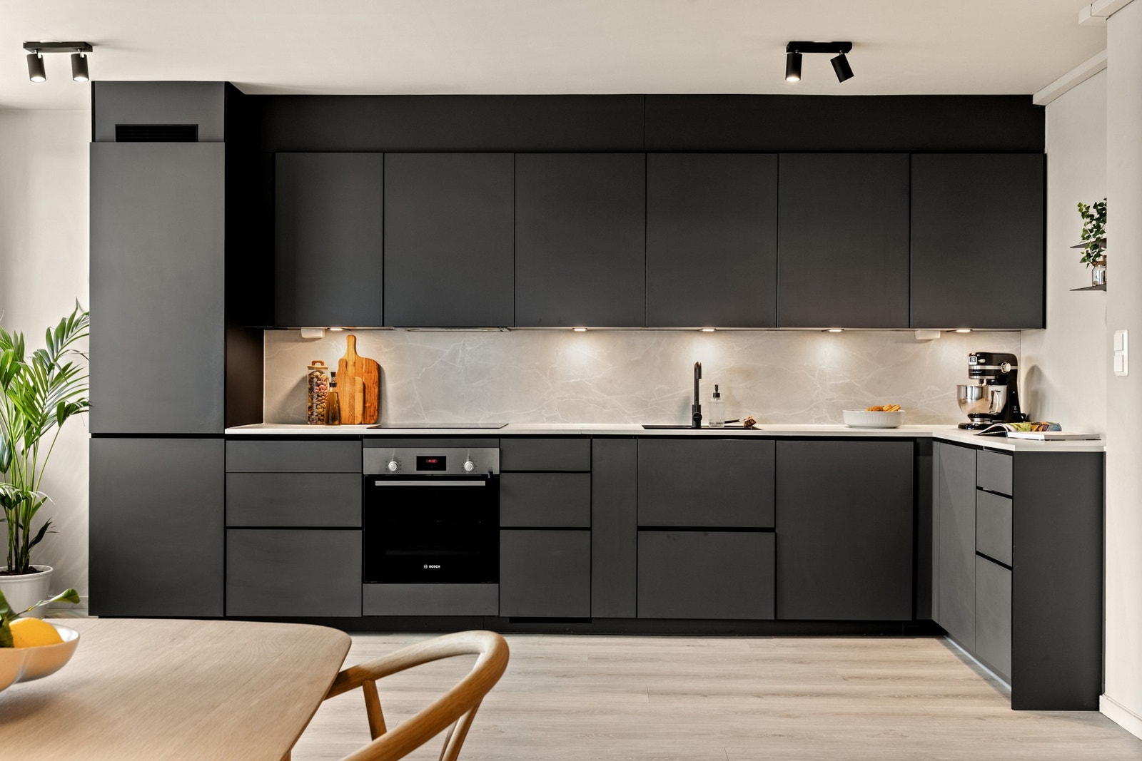 Innredningen er fra Kvik med glatte fronter i grå utførelse. Benkeplaten er i laminat med marmoruttrykk og strekker seg opp på veggen under overskapene, og skaper et sømløst og funksjonelt design. Galleribilde