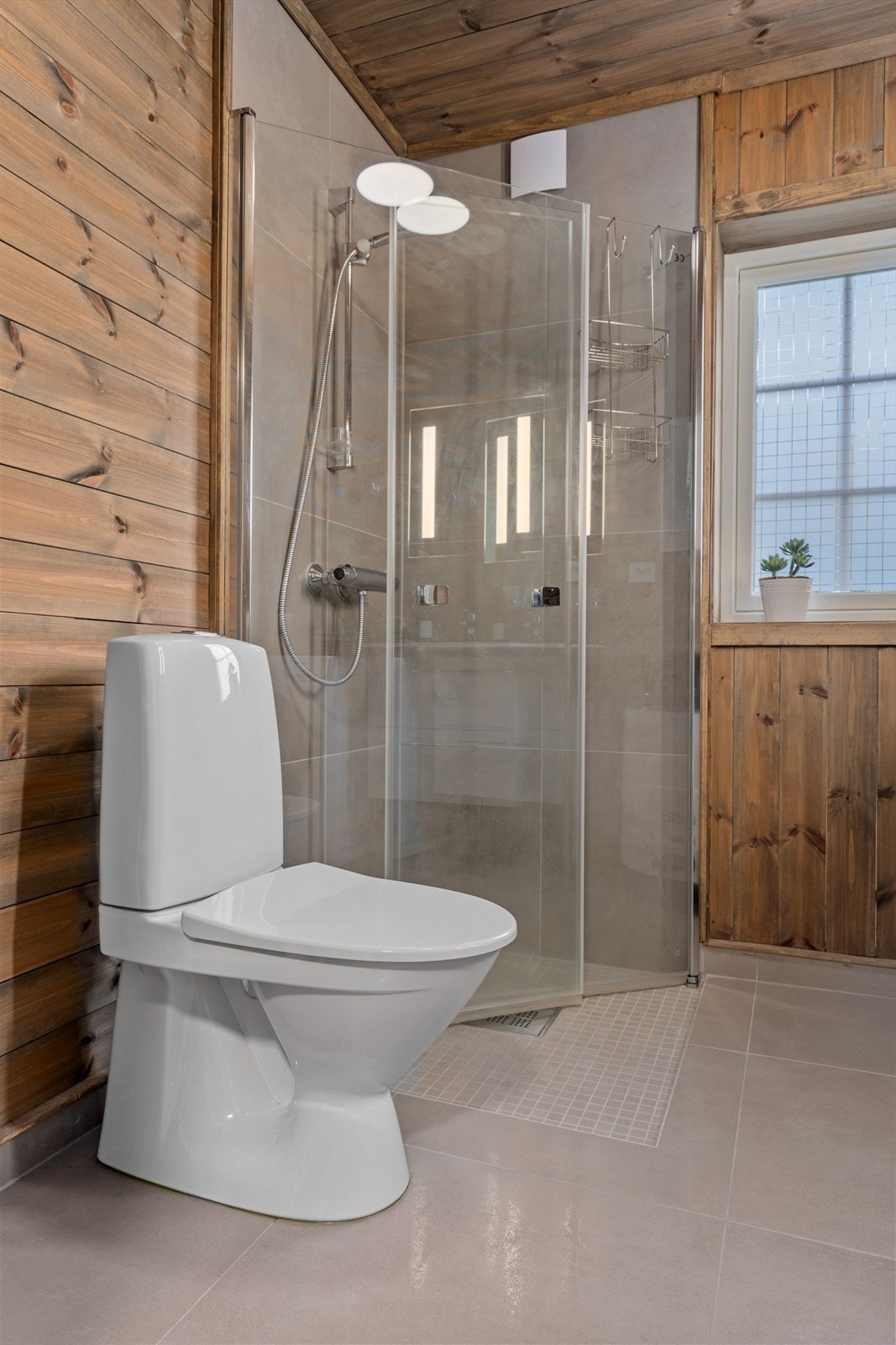 Badet er innredet med toalett, dusjhjørne, servantinnredning og har opplegg for vaskemaskin Galleribilde