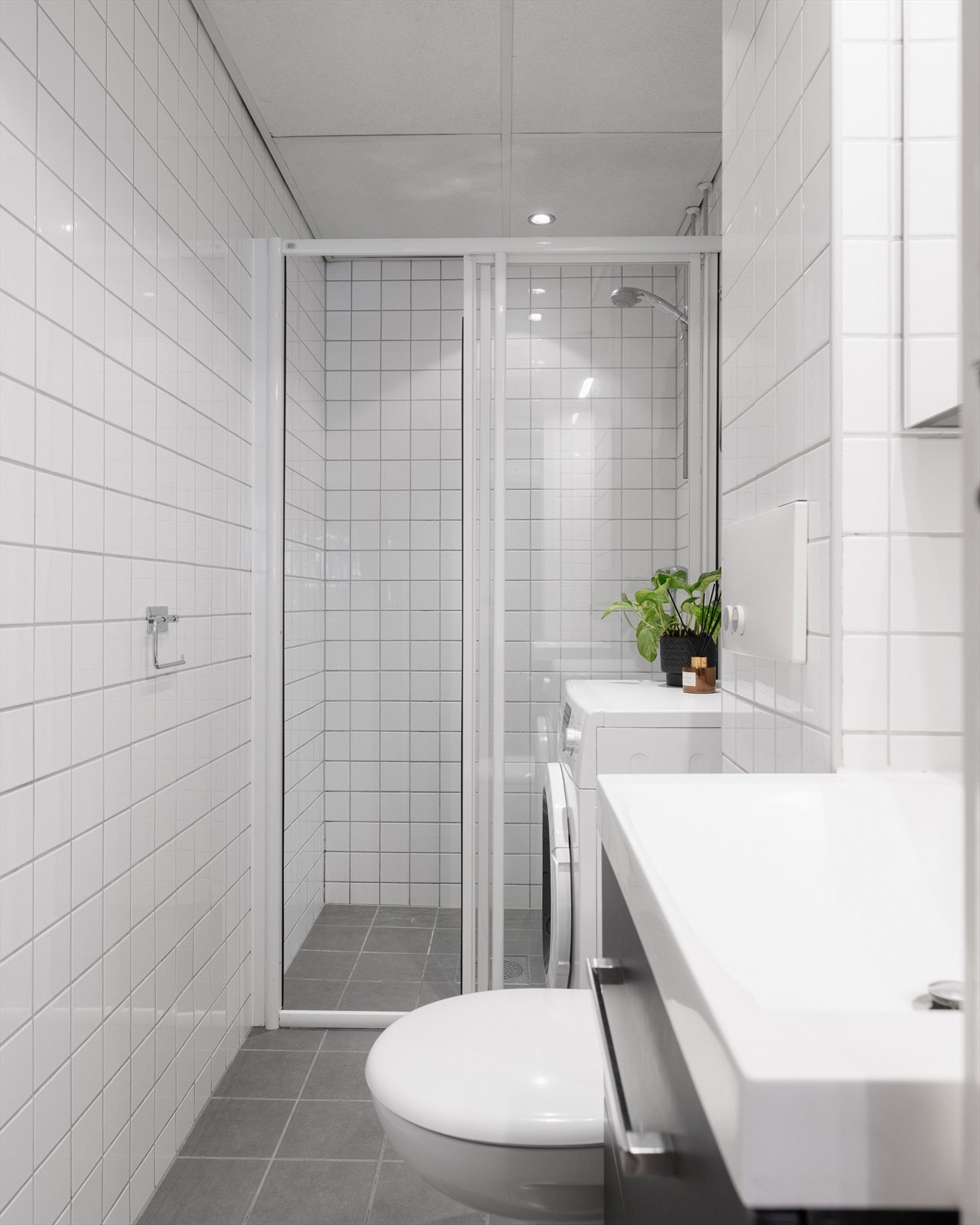 Badet har lyse, flislagte overflater i en tidsnøytral utførelse og varmekabler i gulv. Opplegg for vaskemaskin. Galleribilde