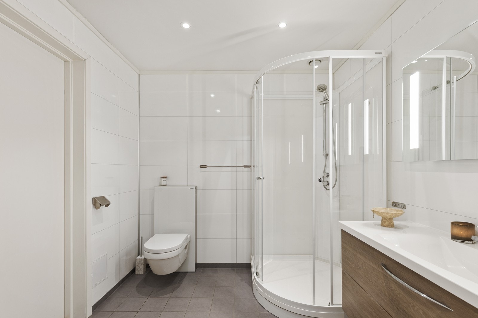 Badet er innredet med servantinnredning med nedfelt servant, vegghengt toalett og dusjkabinett. Galleribilde