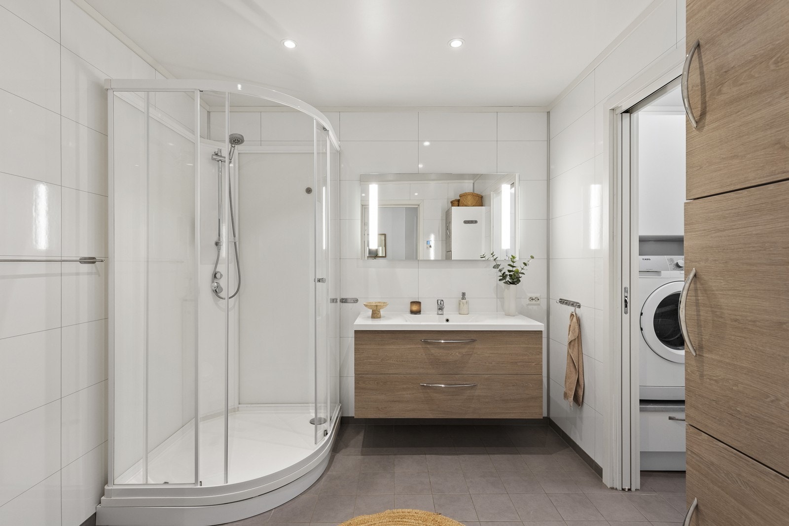 Badet er smakfullt flislagt med nøytrale farger og rene linjer, noe som skaper en harmonisk og avslappende atmosfære. Galleribilde