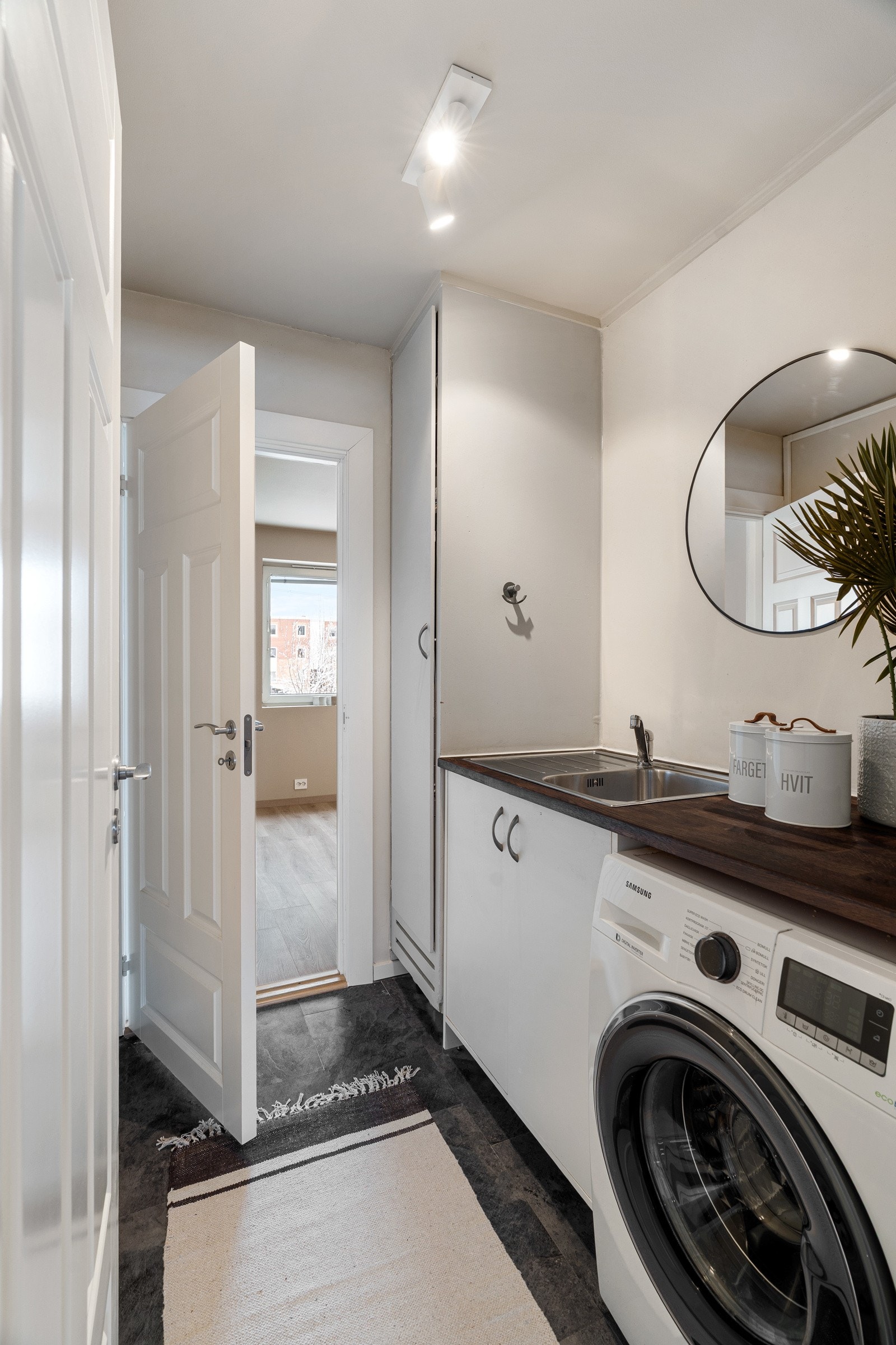 Leilighetens vaskerom er innredet med laminat på gulv og malte slette vegger. Vaskerommet har gode oppbevaringsmuligheter i skap og benkeplate med nedfelt kum. Det er etablert lekkasjeføler i benkeskap og gulv. Galleribilde