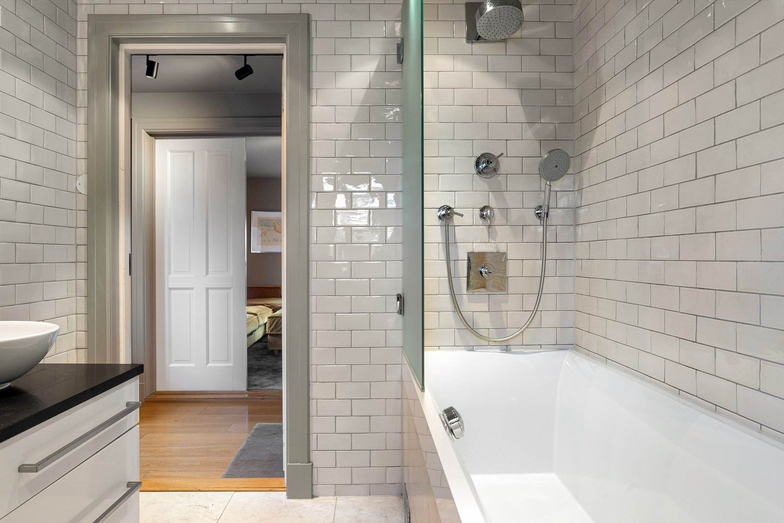 Innredning med skuffer og sort benk med toppmontert servant. Veggmontert wc. Innbygget badekar med svingbar dusjdør i herdet gass, samt vannfallsdusj og hånddusj Galleribilde