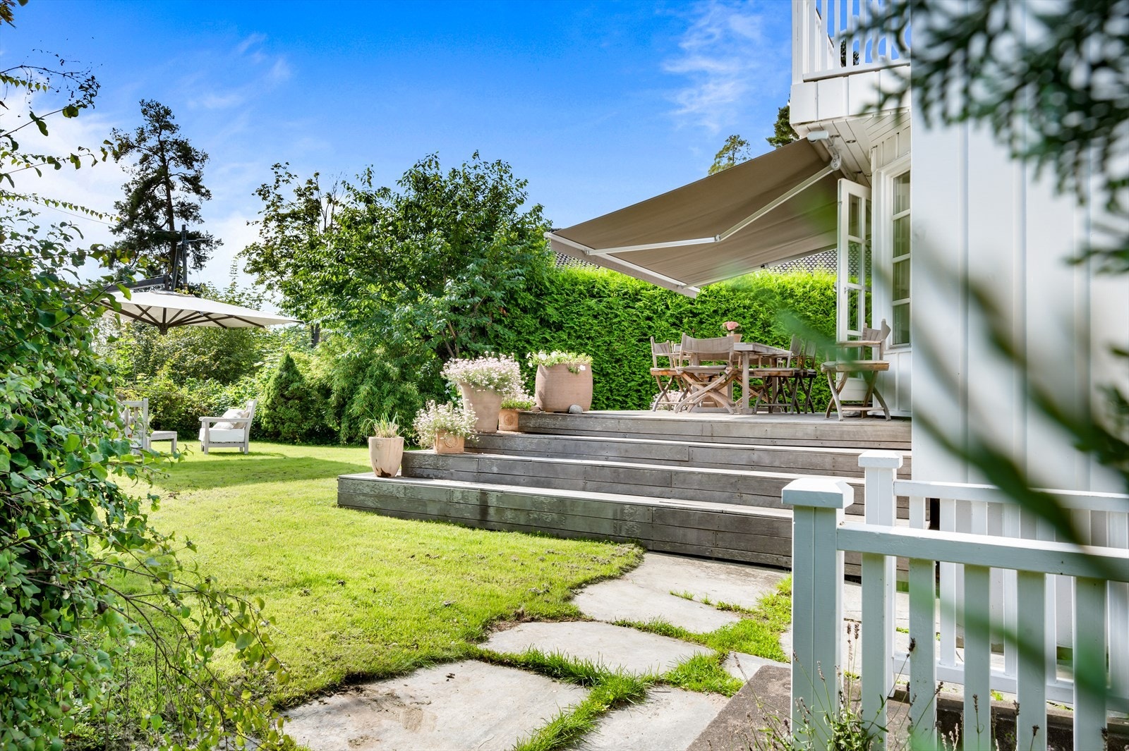 Stor og flat gressplen med god plass til flere sittegrupper, solstoler, trampoline, lekestativ, dukkestue m.m. Galleribilde