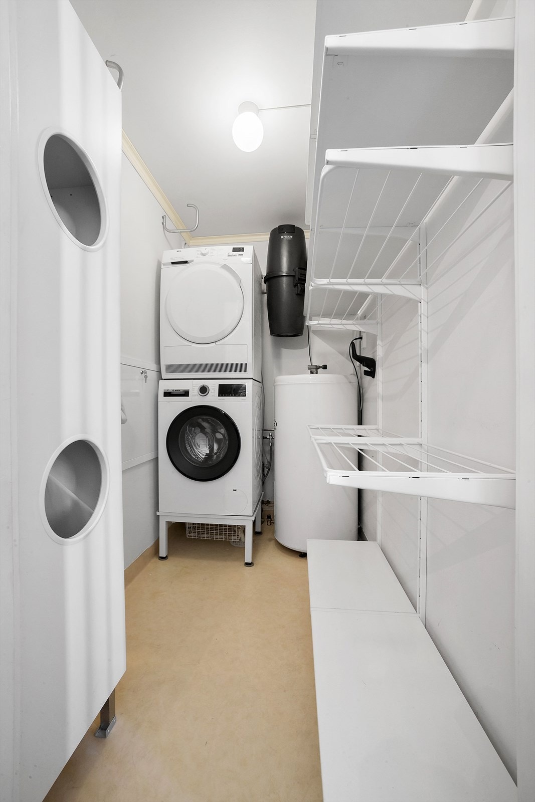Vaskerom med hylleløsninger og sentralstøvsuger. Her er det gode oppbevaringsmuligheter. Galleribilde