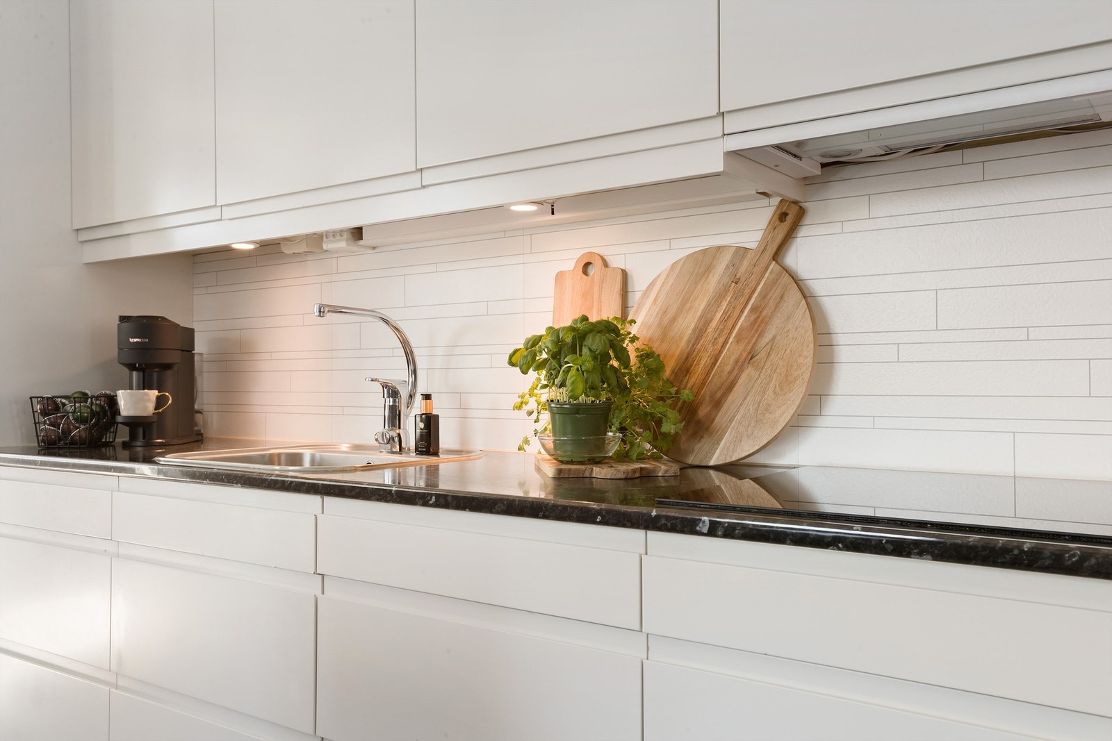 Kjøkkeninnredningen er fra Norema og har hvite, slette fronter med benkeplate av laminat Galleribilde