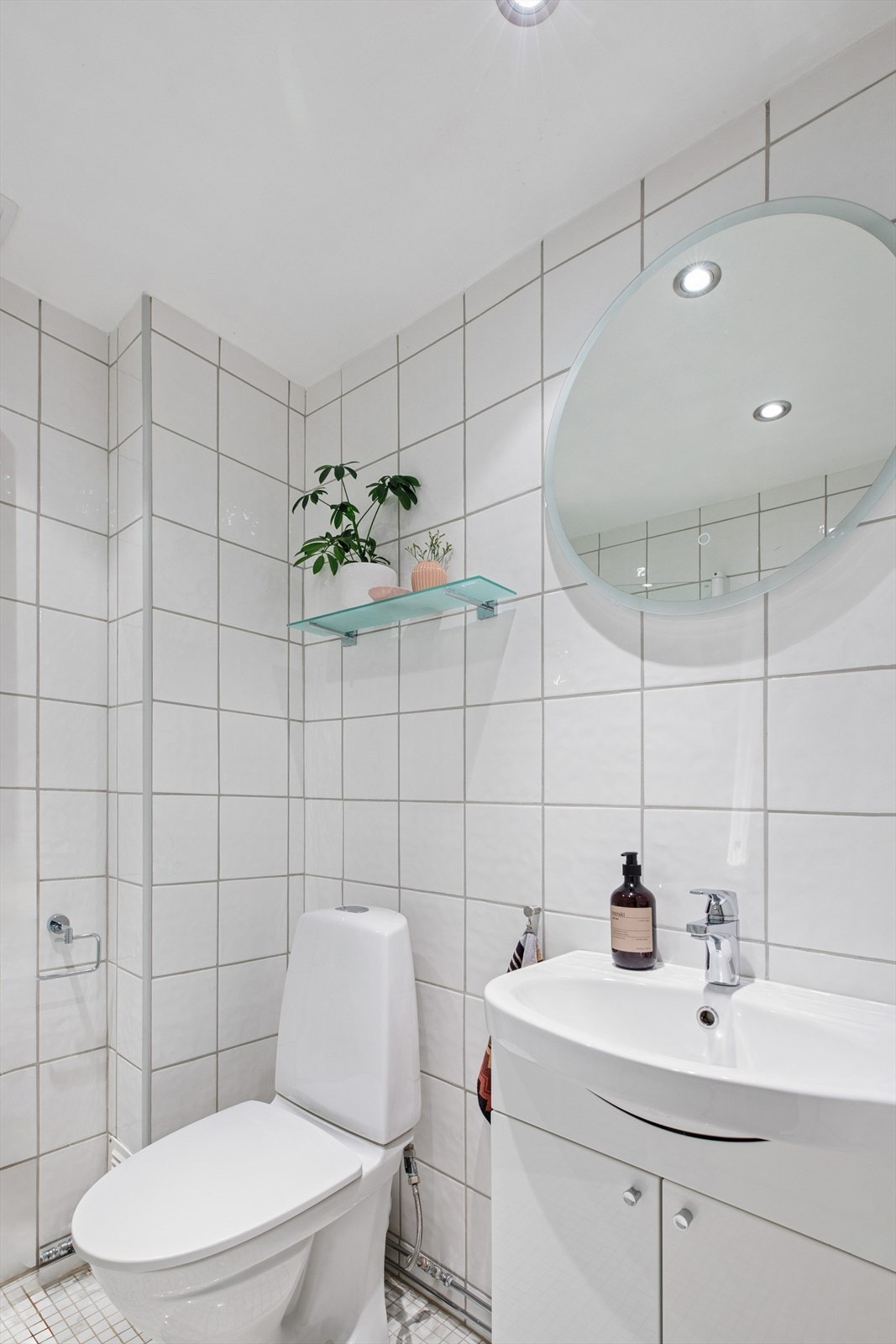 Videre er badet utstyrt med gulvmontert wc, baderomsinnredning med heldekkende servant og speil med lys. Galleribilde