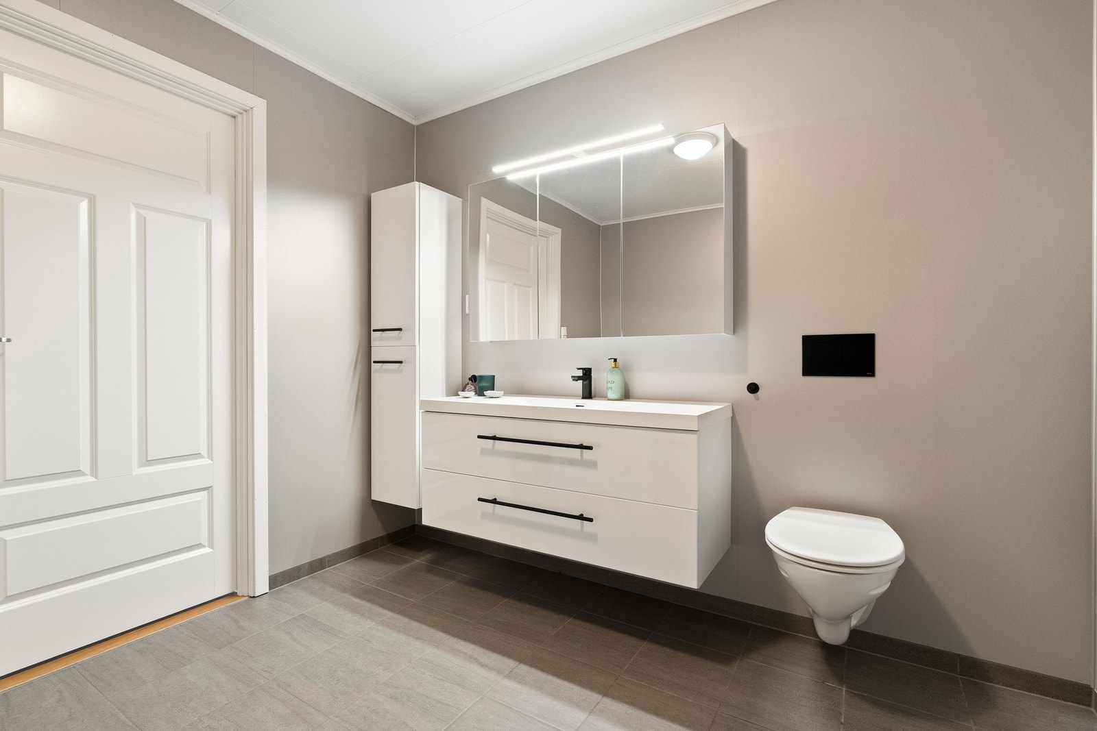 Badet er utstyrt med baderomsinnredning, vegghengt toalett og dusjhjørne. Galleribilde