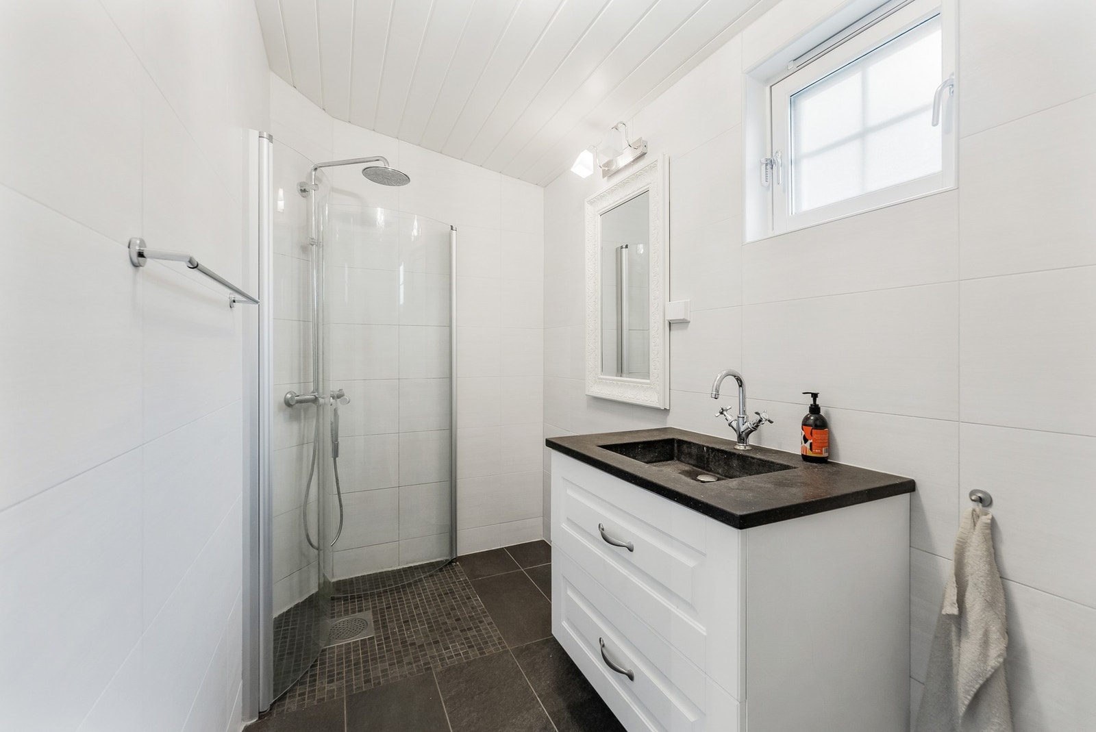 Flislagt baderom med gulvvarme. Vegghengt servantinnredning med speil med overlys. Galleribilde