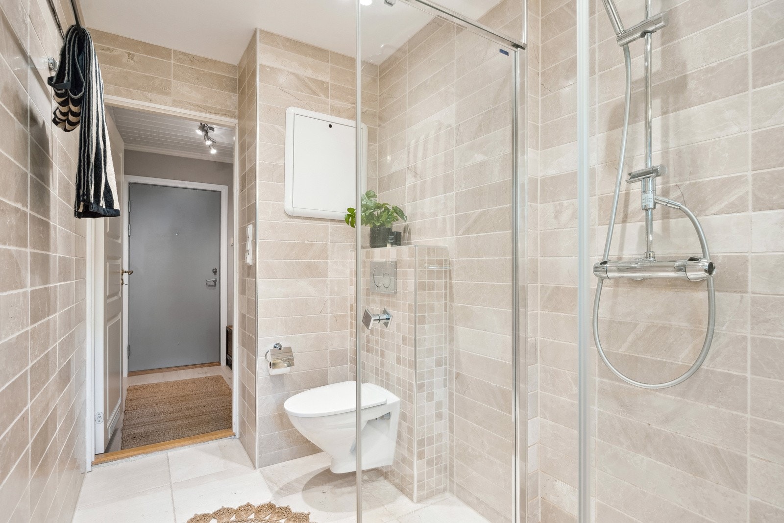 Badet er utstyrt med vegghengt servantinnredning, vegghengt toalett, dusjhjørne med dører og opplegg til vaskemaskin. Galleribilde