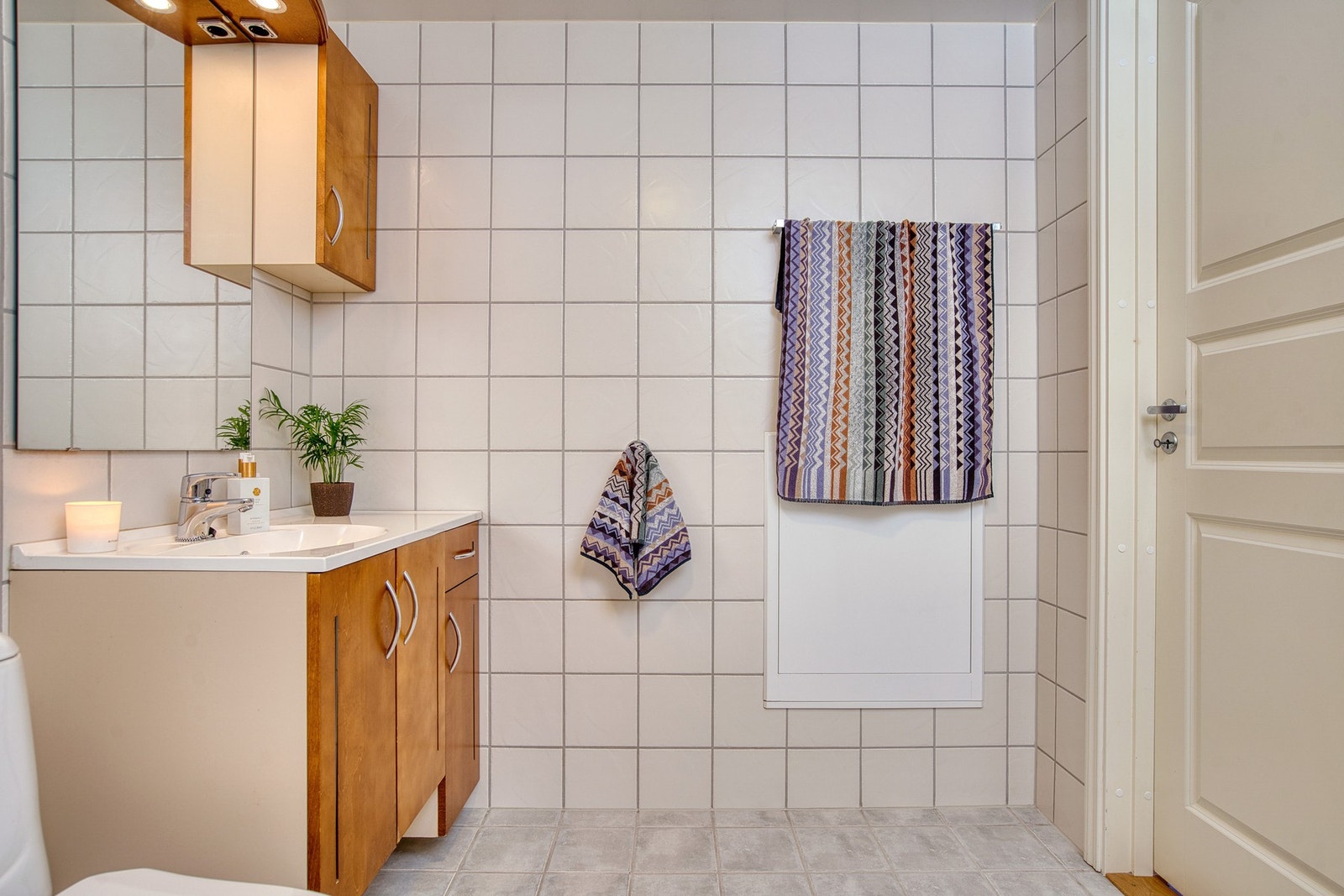 Flislagt bad med nedfelt servant, toalett, dusjhjørne og opplegg for vaskemaskin. Galleribilde