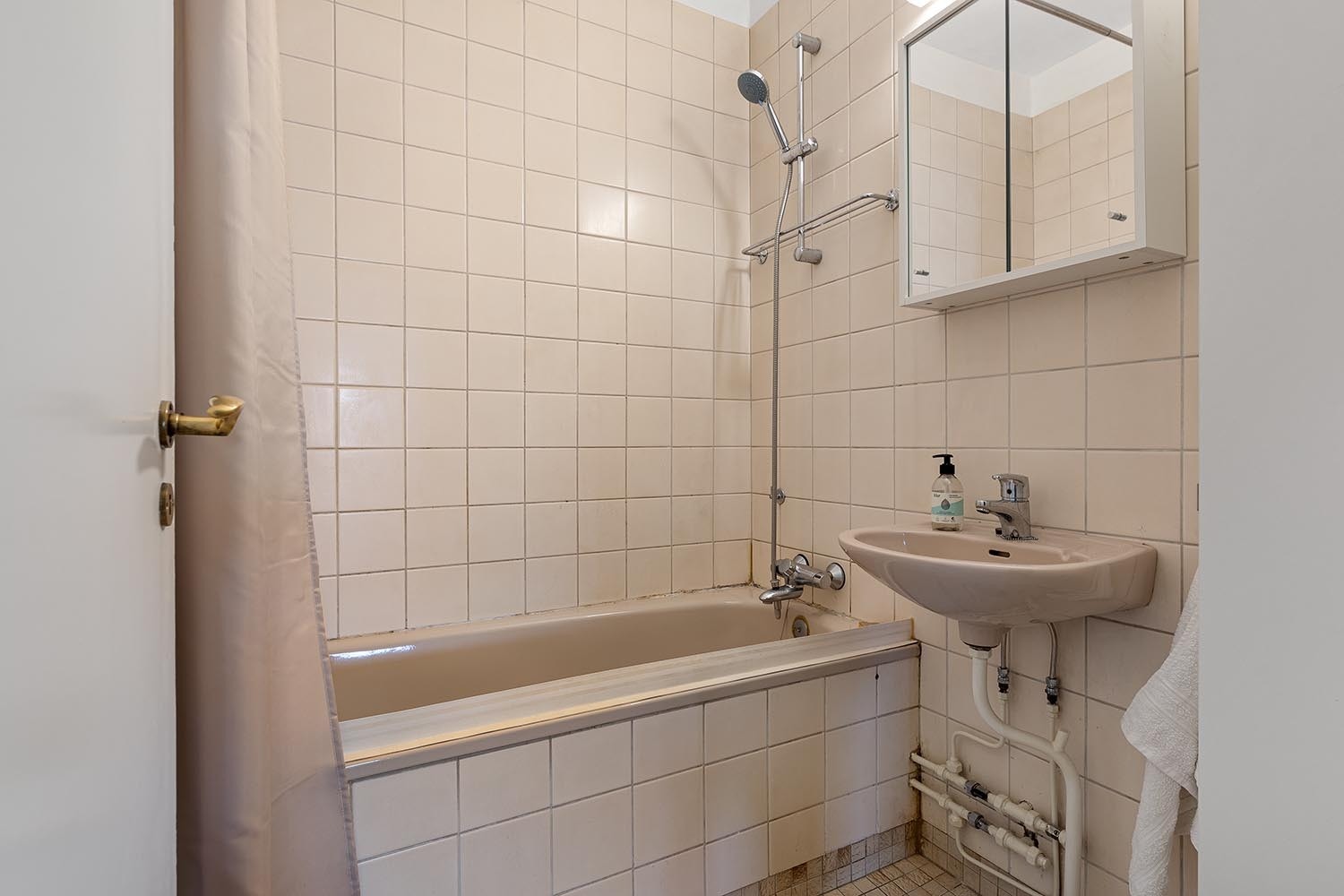Badet er flislagt og har en moderne innredning i beige toner. Det er utstyrt med vaskemaskin og har god oppbevaringsplass. Galleribilde