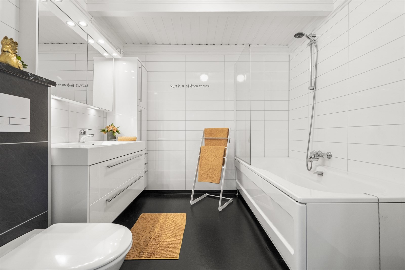 Romslig bad med vegghengt toalett, servant i innredning og dusj i badekar Galleribilde