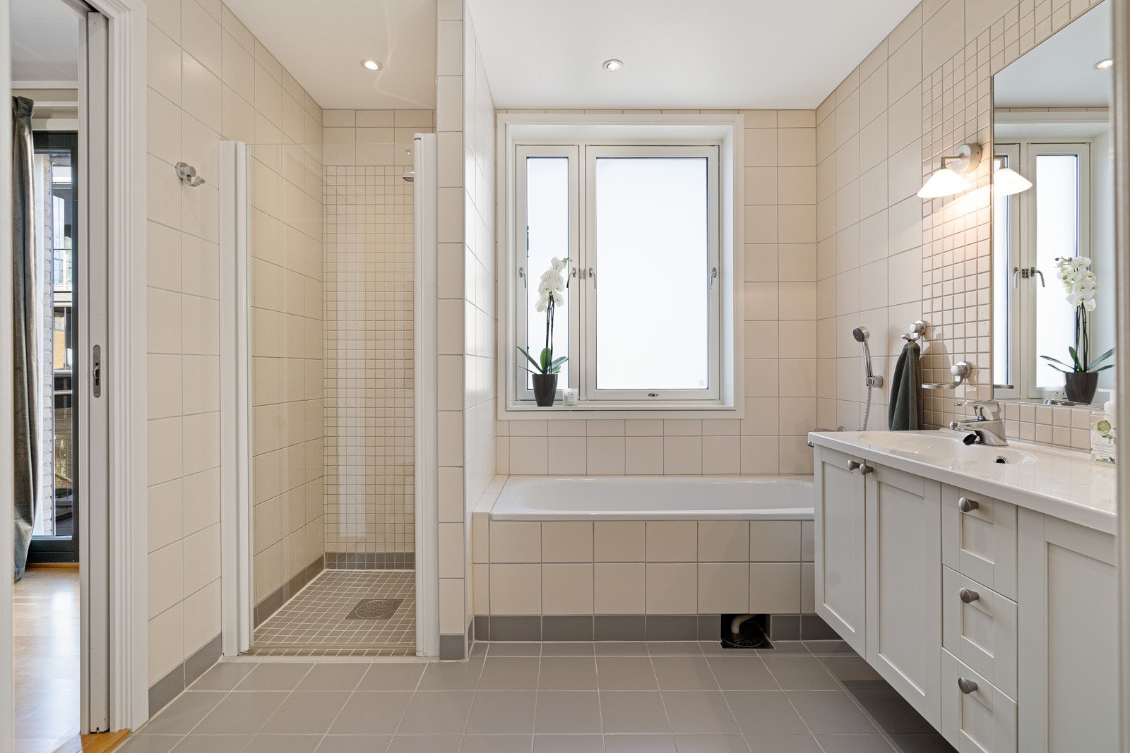 Badet er innholdsrikt og stilrent med dobbel servant, underskap, speil med sidebelysning, badekar og egen dusjnisje. Galleribilde