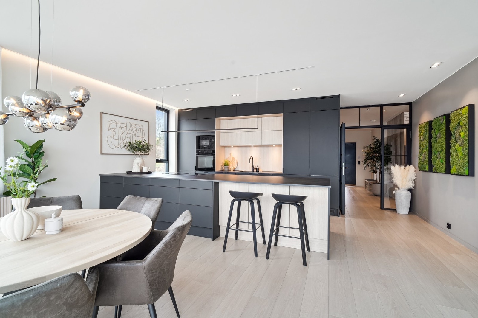 Kjøkkenet fremstår skreddersydd med en stilren kombinasjon av mørke, matte fronter og trehvite detaljer. Galleribilde