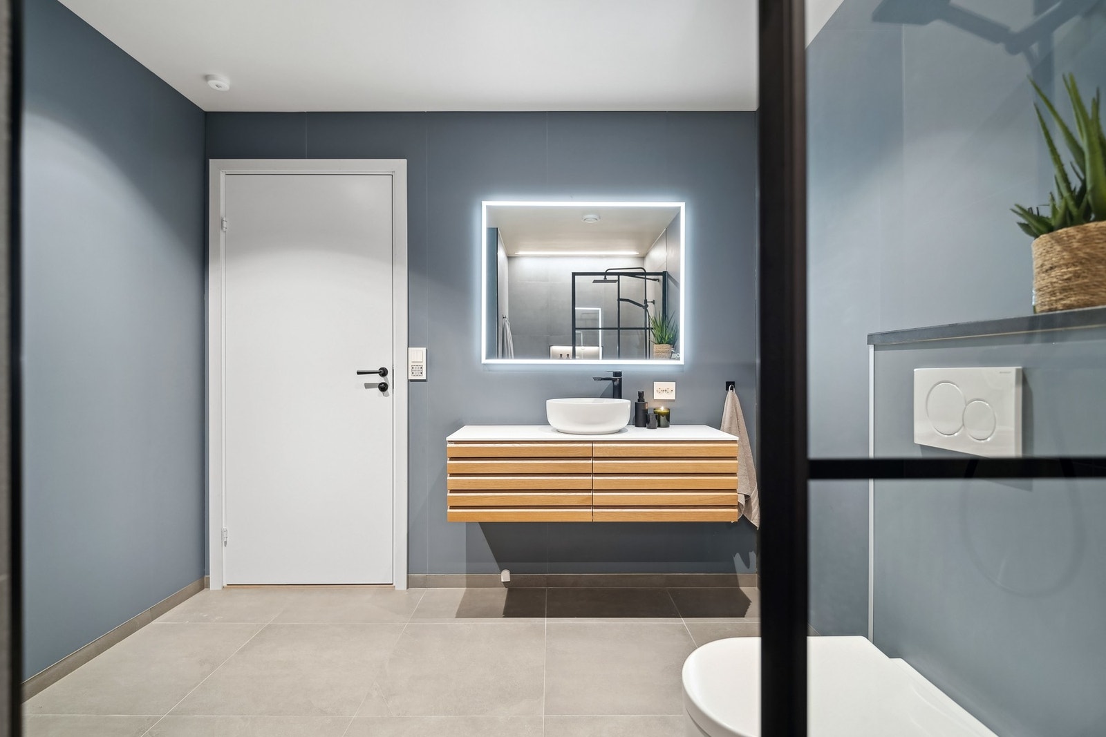 Badet er stilrent og malt i en rolig blåtone som kler boligen. Galleribilde