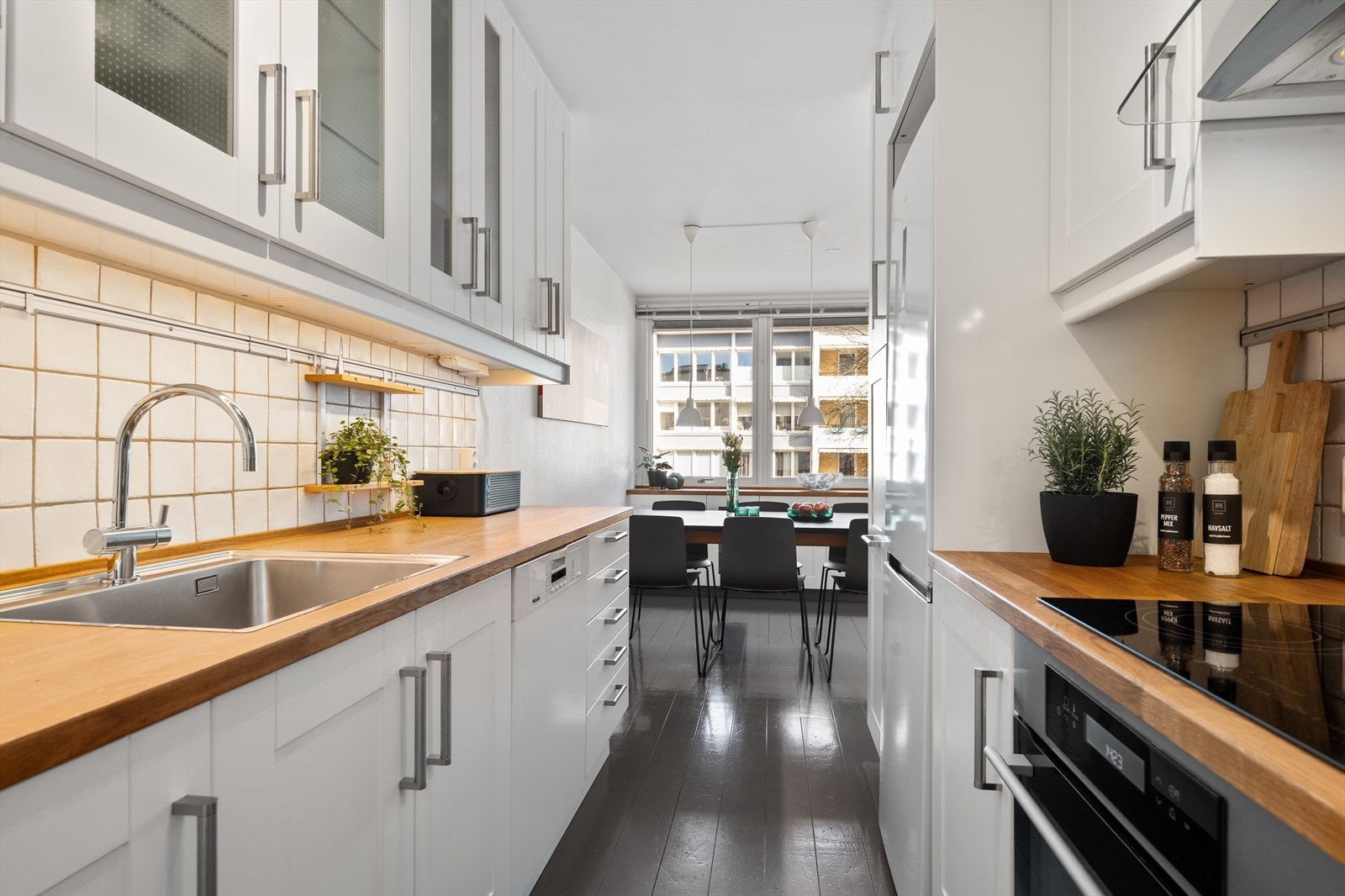 Kjøkkenet har hvite profilerte skapdører, fliser over kjøkkenbenken og integrerte hvitevarer. Galleribilde