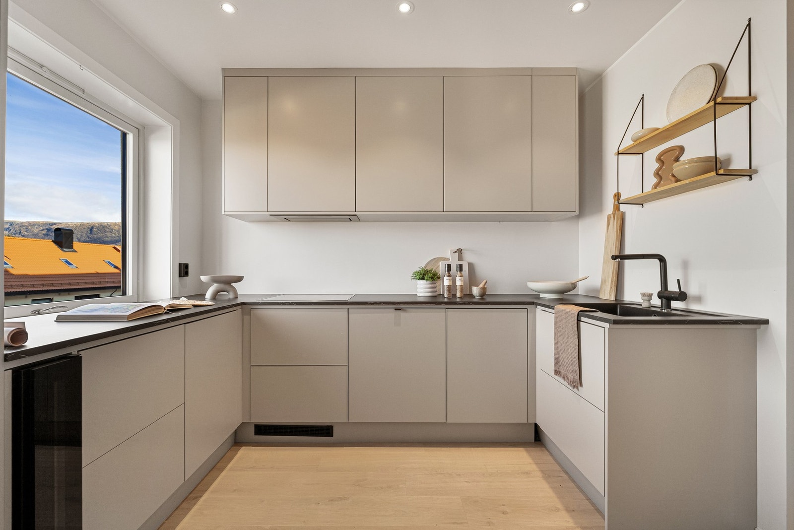 Kjøkkenet er delikat og tidløst innredet med slette beige fronter og pen benkeplate i laminat Galleribilde