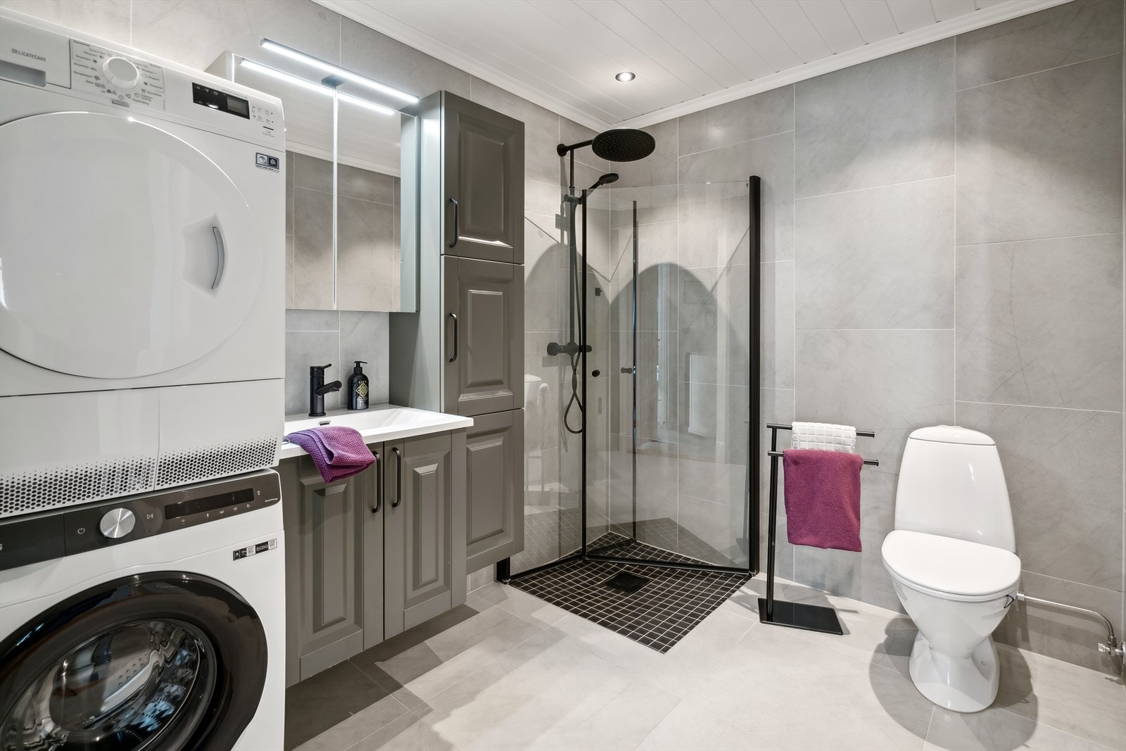 Badet i 1.etasje er flislagt, og har dusjhjørne, wc, servant og opplegg for vaskemaskin Galleribilde