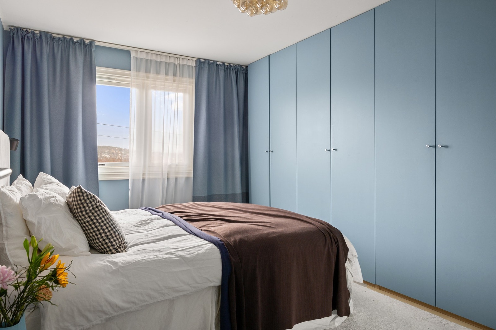 Hovedsoverommet kombinerer funksjonalitet og stil med romslige garderobeskap malt i samme beroligende blåfarge som veggene. Galleribilde