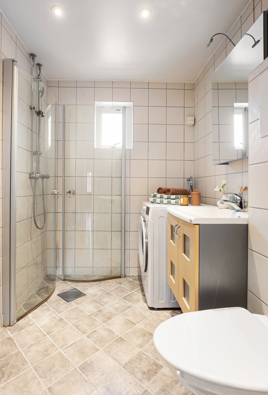 Baderomsinnredningen består av vegghengt toalett, servantinnredning, servant med ettgreps blandebatteri, speilskap, dusjarmatur, plass og opplegg for vaskemaskin. Galleribilde