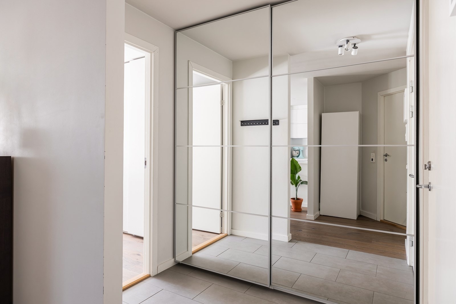 Innbydende entré med flislagt gulv og god oppbevaringsplass i en stor skyvedørsgarderobe med speilfronter. Galleribilde