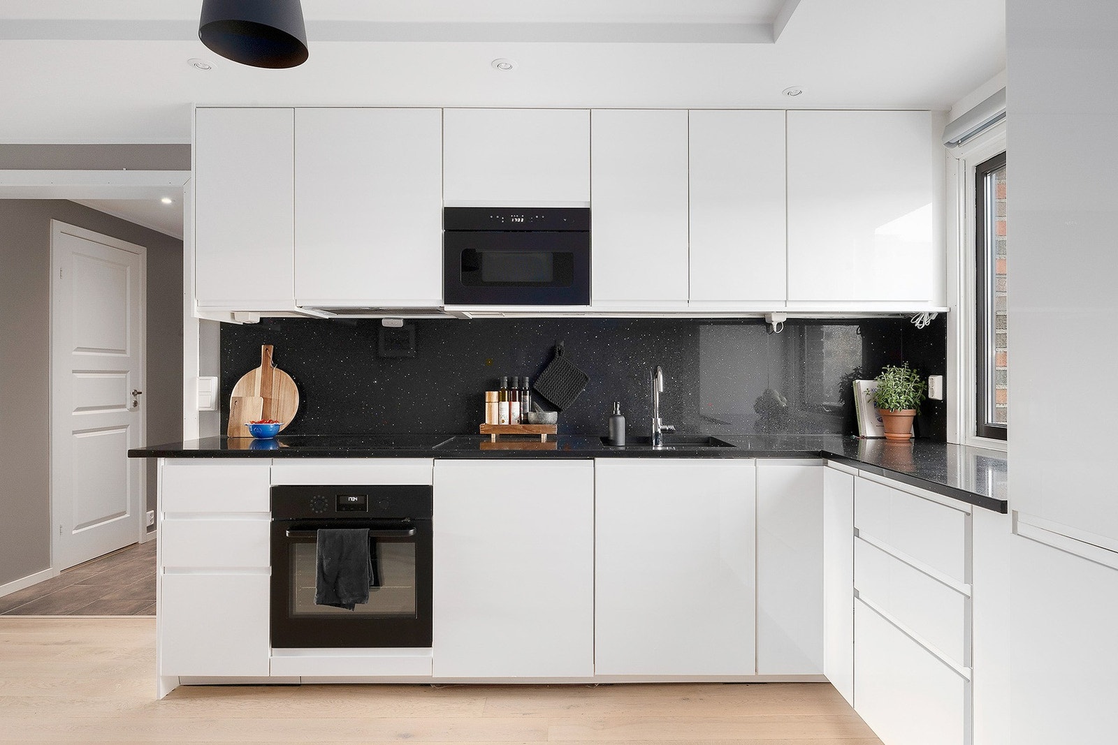 De glatte frontene og benkeplaten i kvarts gir et rent og stilrent uttrykk, mens de integrerte hvitevarene gjør matlagingen enkel og effektiv. Galleribilde