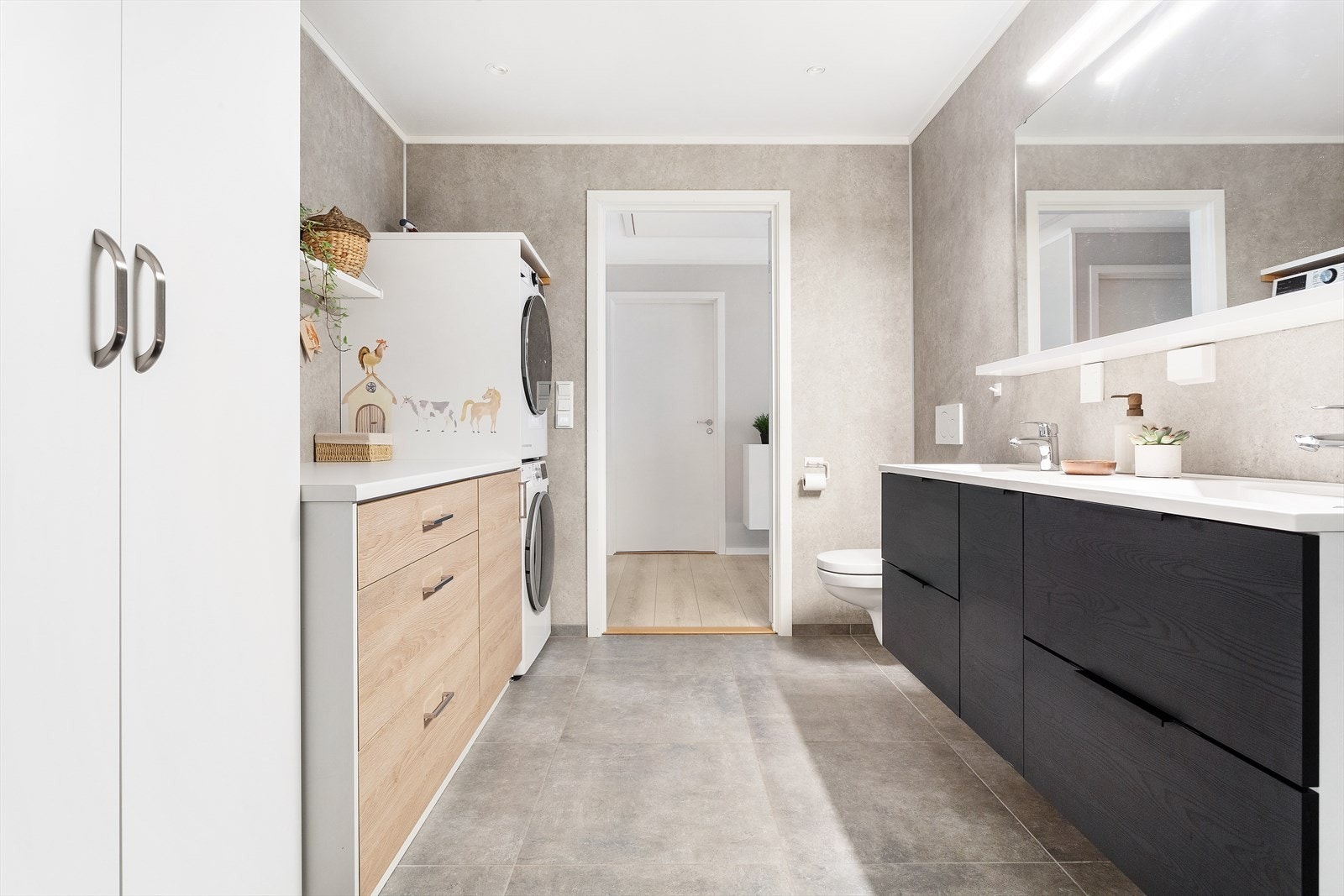 Flott sort baderomsinnredning med 2 servanter. Her er det også montert vaskeromsinnredning og garderobeskap. Spotter i tak. Galleribilde