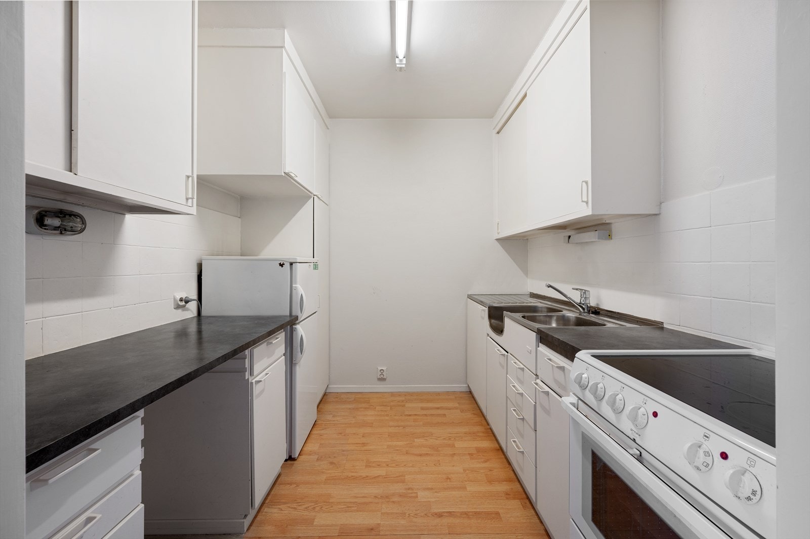 Kjøkkenet er innredet med laminert benkeplate, slette fronter, opplegg for komfyr og fliser mellom benkeplate og overskap. Galleribilde